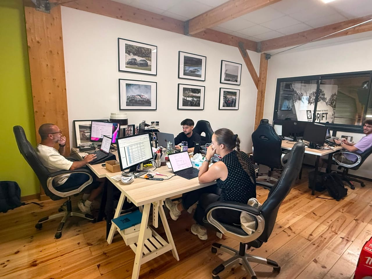 Open space du cowork ADAMYA, les équipes au travail sous le mur de photos du Championnat de France de drift
